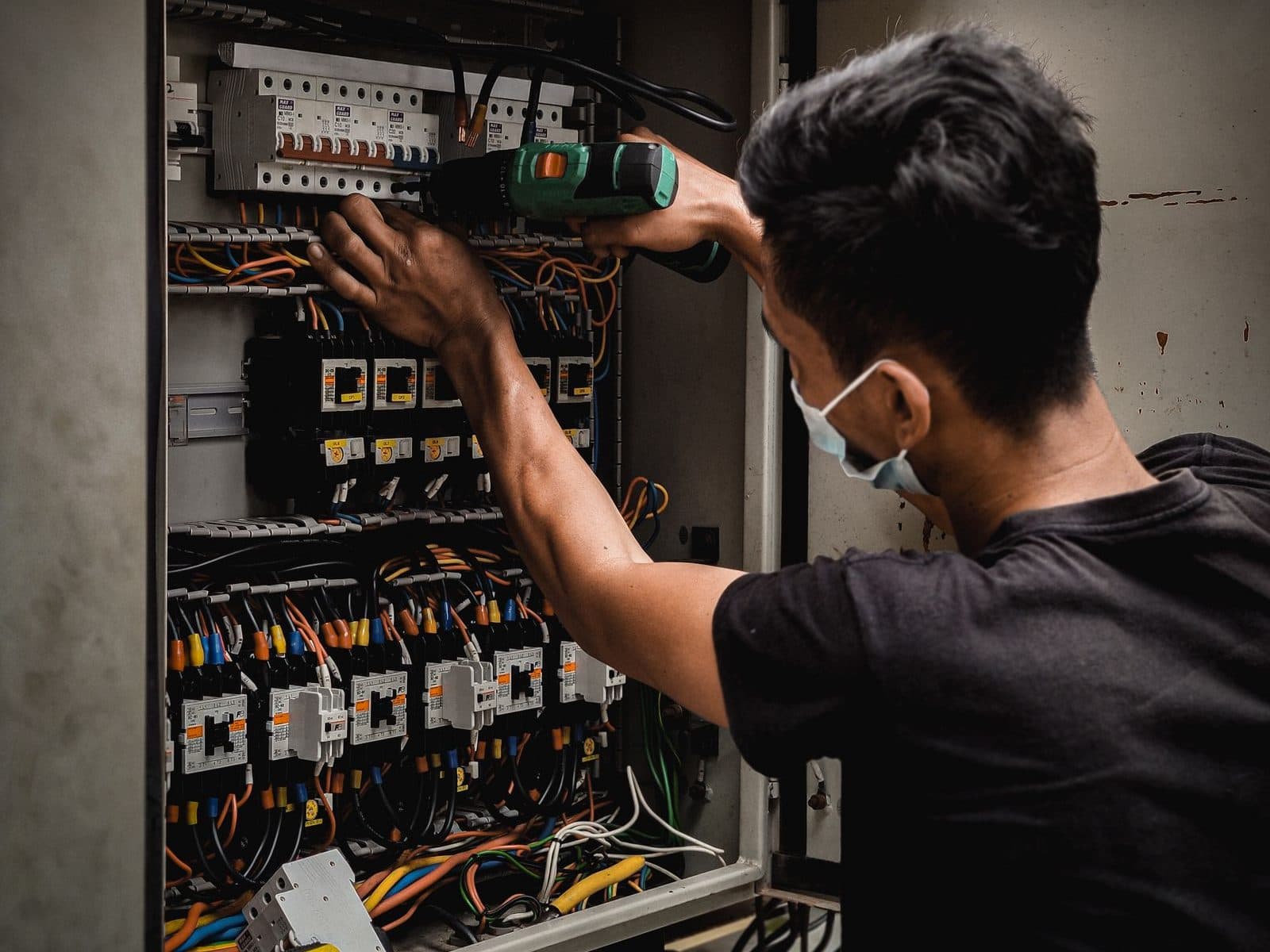 Technicien intervenant dans une armoire électrique de local professionnel, protections et borniers repérés